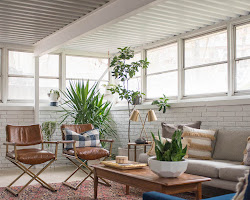 A sunroom with a cozy seating area, a fireplace, and plenty of plants-Interior Design